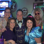 A group of five adults in colorful costumes at a party.