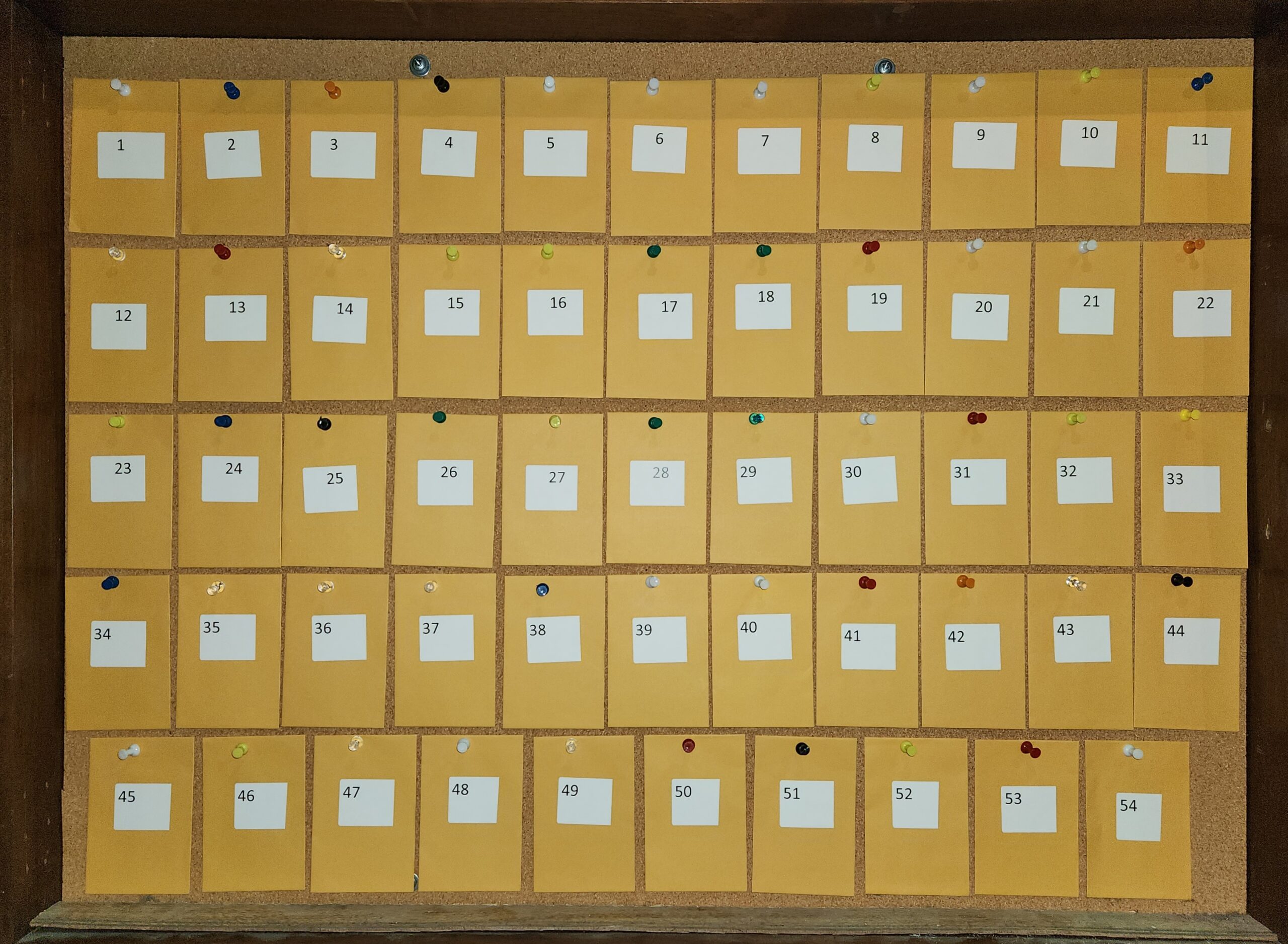 A wooden filing cabinet with labeled drawers arranged in a grid.